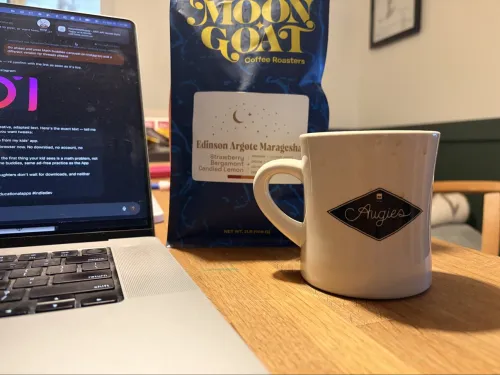 Moon Goat coffee bag next to a white mug of brewed coffee
